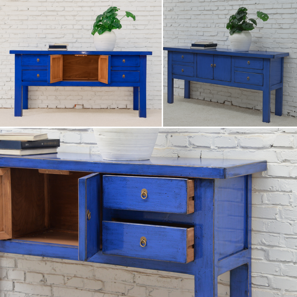 Blue wooden desk with open drawers against a white brick wall.
