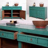 Teal wooden sideboard with open doors against a white brick wall.