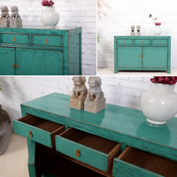 Teal wooden sideboard with drawers against a white brick wall.