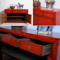Red wooden sideboard with open drawers and decorative items on a white background