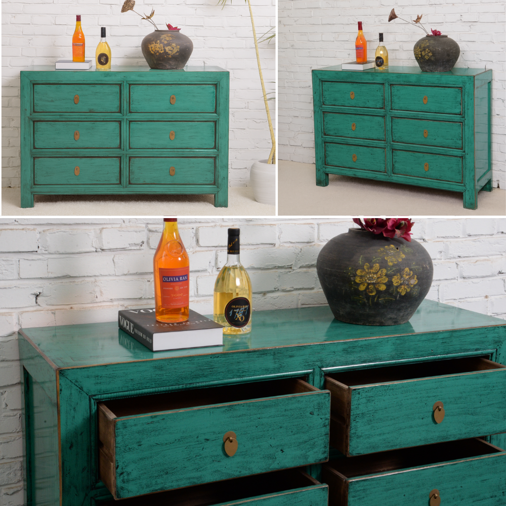 Teal dresser with decorative items against a white brick wall.